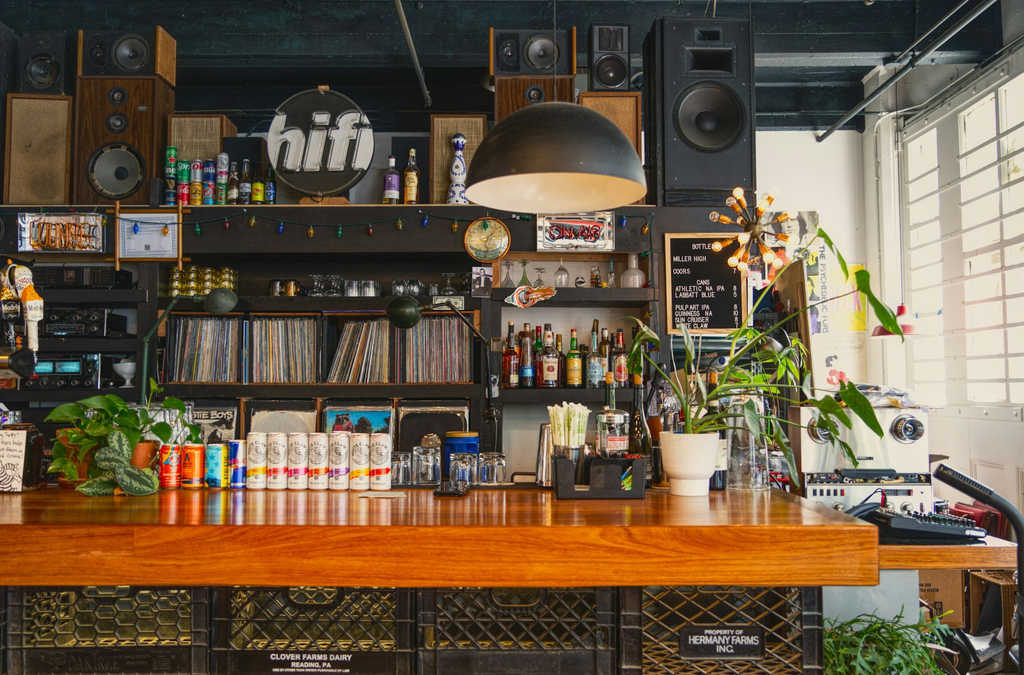 A wooden bar counter in a music venue, plants and low light behind it