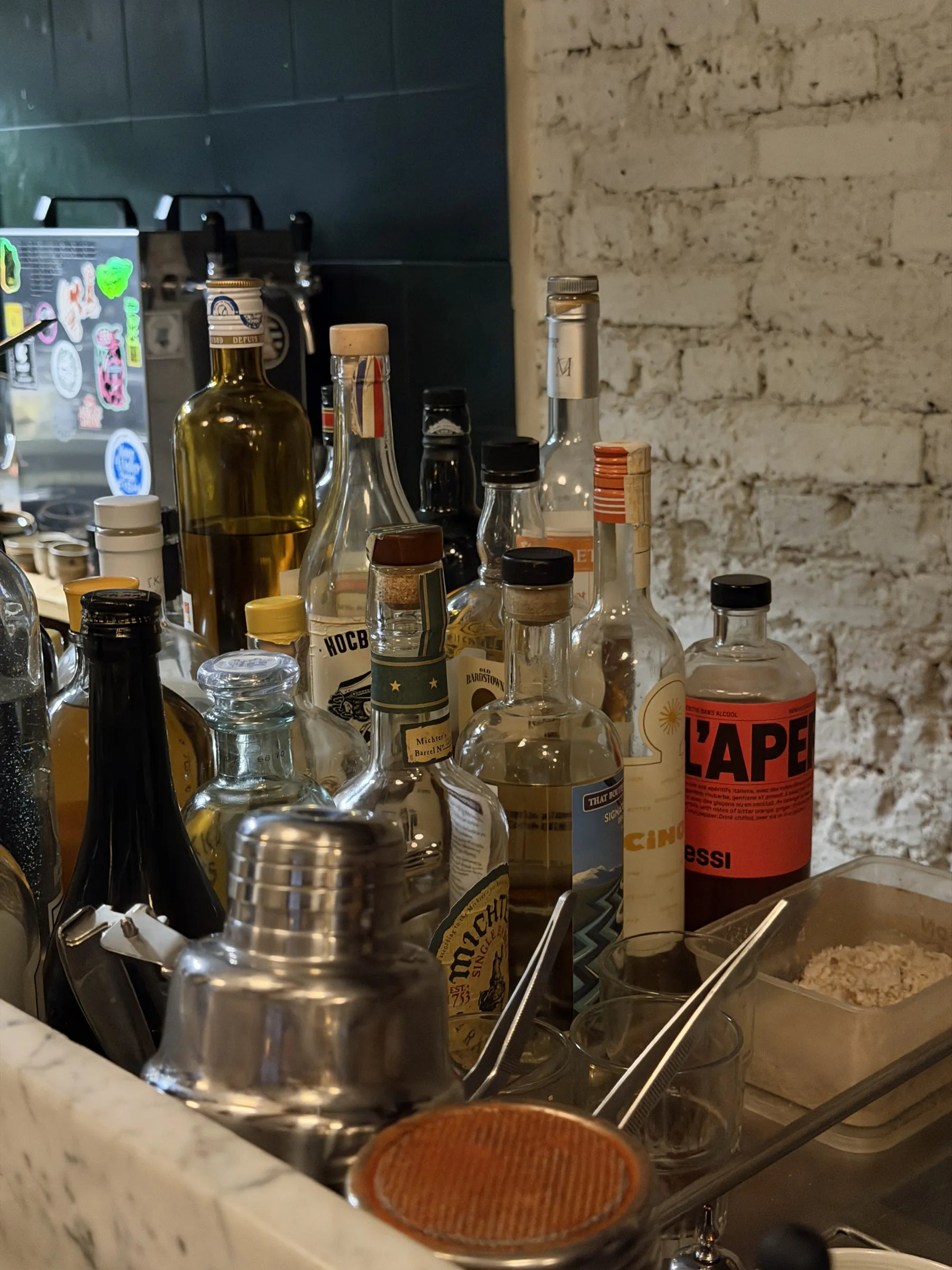Bottles along the back bar at Mesures, Paris, against a whitewashed brick wall