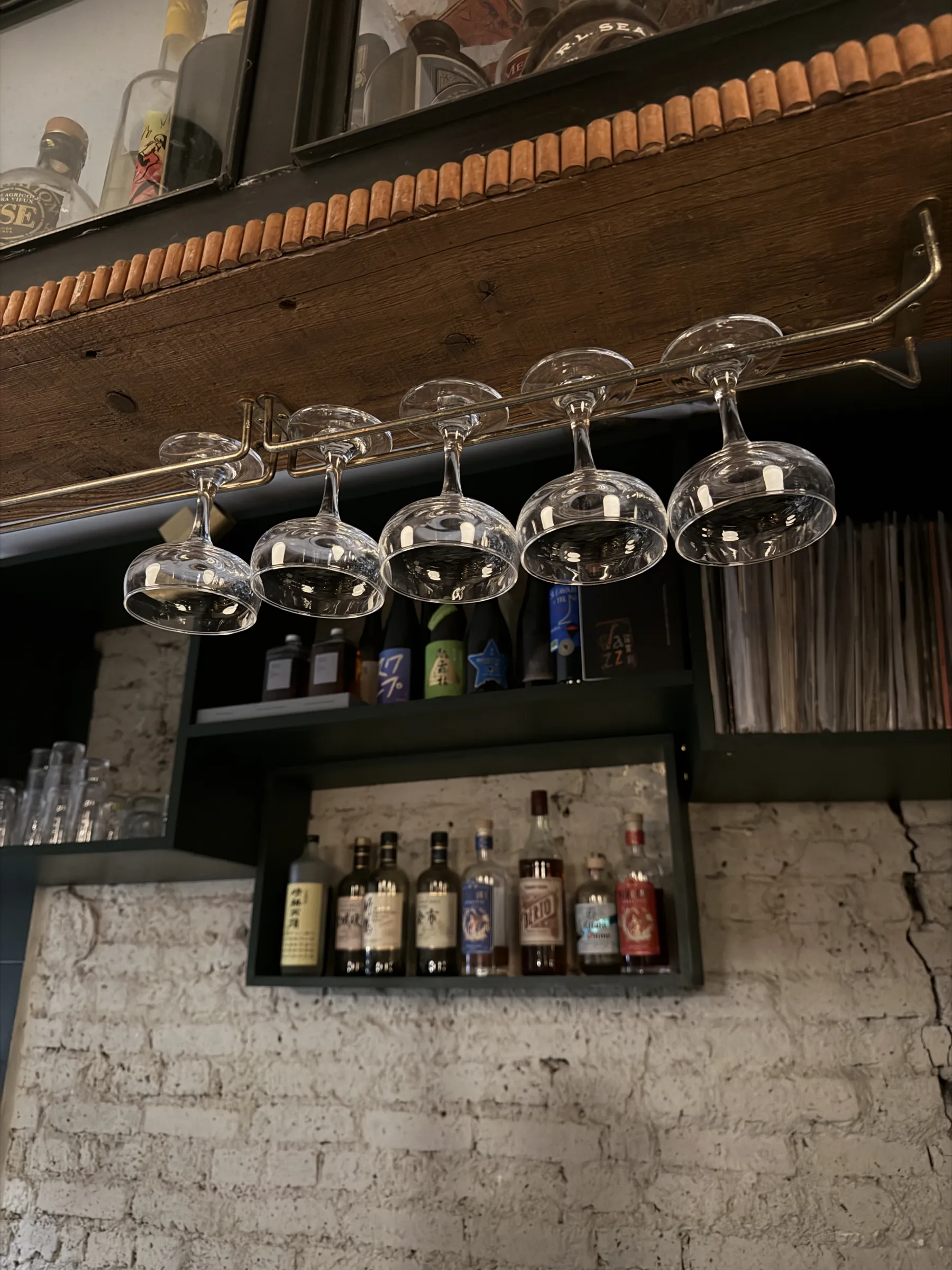 Wine glasses hanging above the bar at Mesures, Paris, with spirits on the shelf below