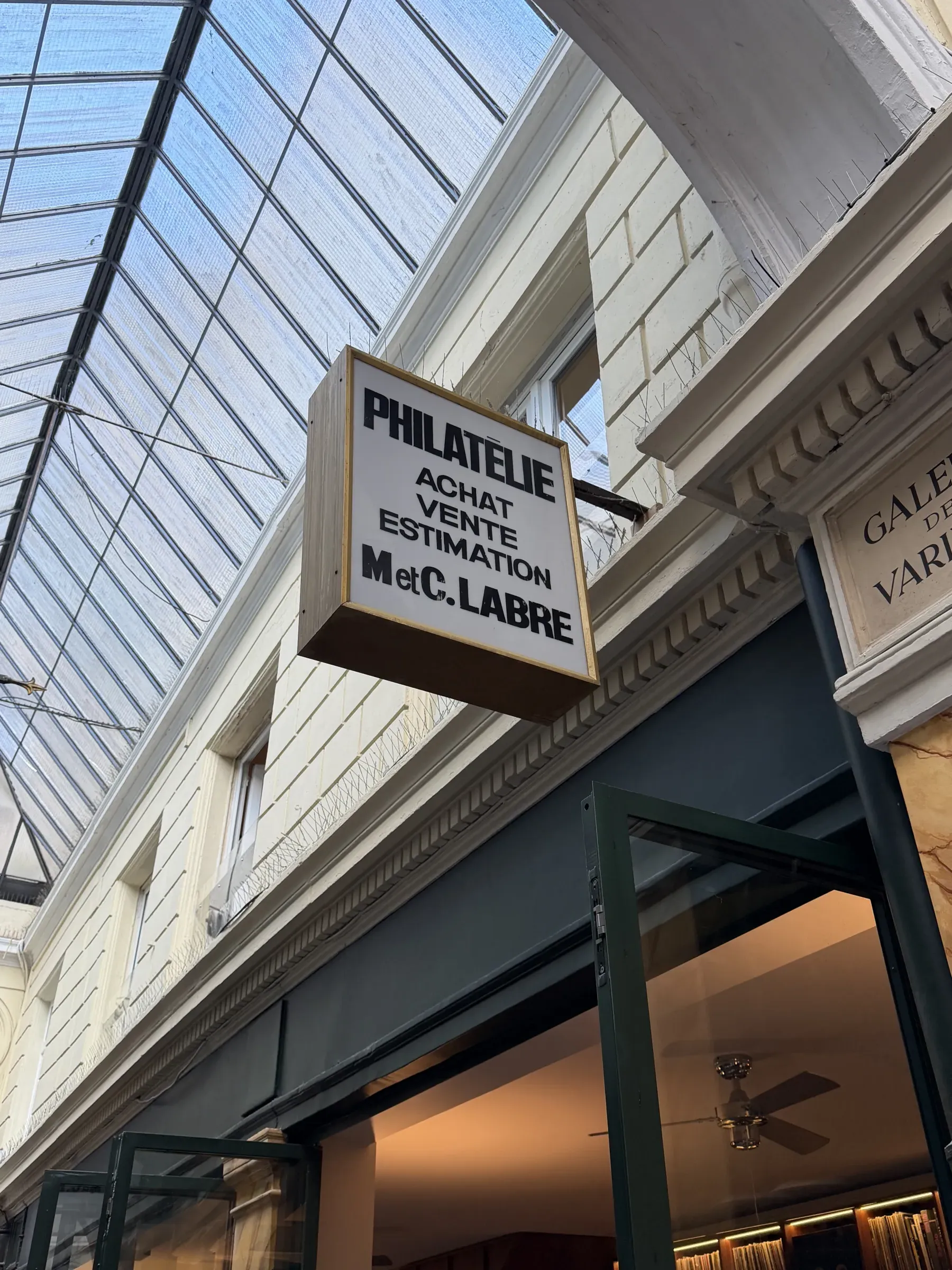 A hanging philately sign under the glass roof of Passage des Panoramas, Paris